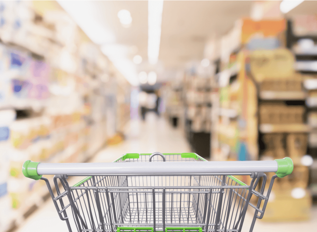 An image of a grocery store aisle from the point of view of a shopper behind a cart.
